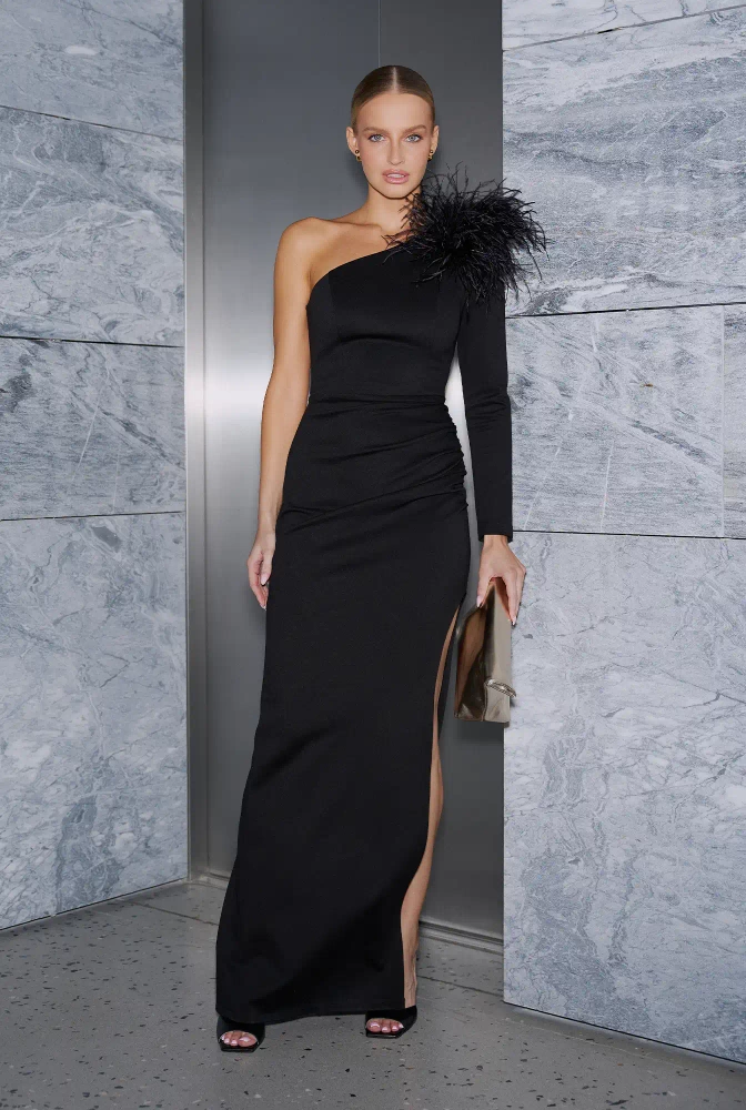 																							Elegante – black asymmetrical maxi dress with a feather brooch
																					